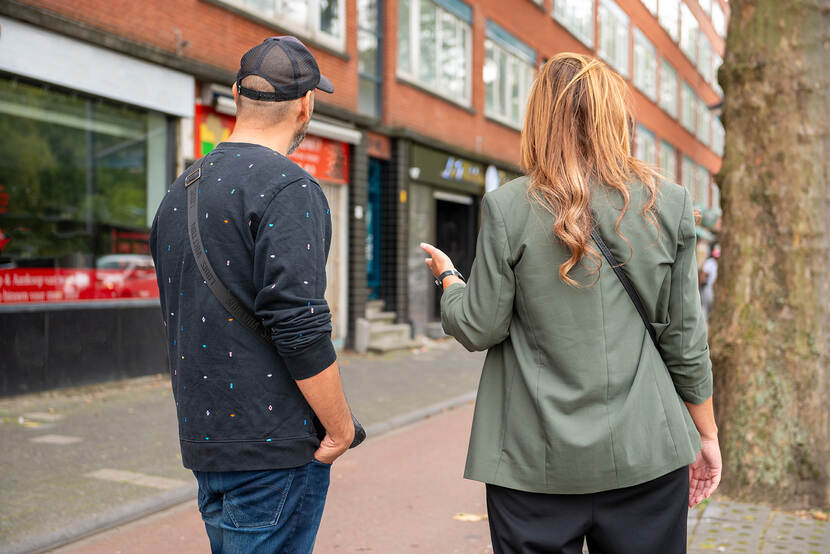 Redouan Azelmad, ervaringsdeskundige en nu eigenaar van zijn eigen bedrijf R.A en Cynthia Blok van Reclassering Nederland staan met hun  rug naar de camera in een straat.