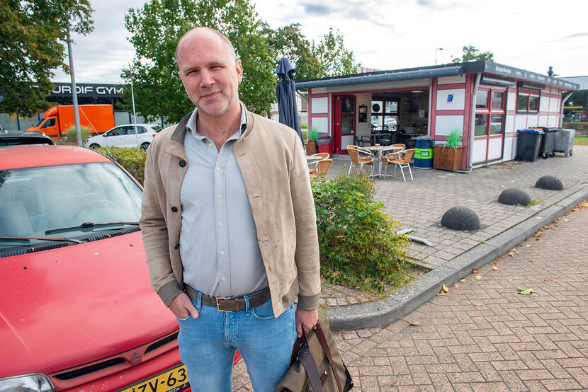 Ondernemer Bob Scherrenberg staat voor een rode auto en kijkt in de camera