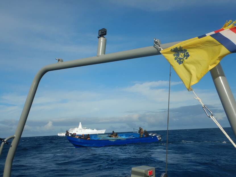 Foto vanaf een boot met uitzicht op een klein bootje waarin gewapende mannen zitten.