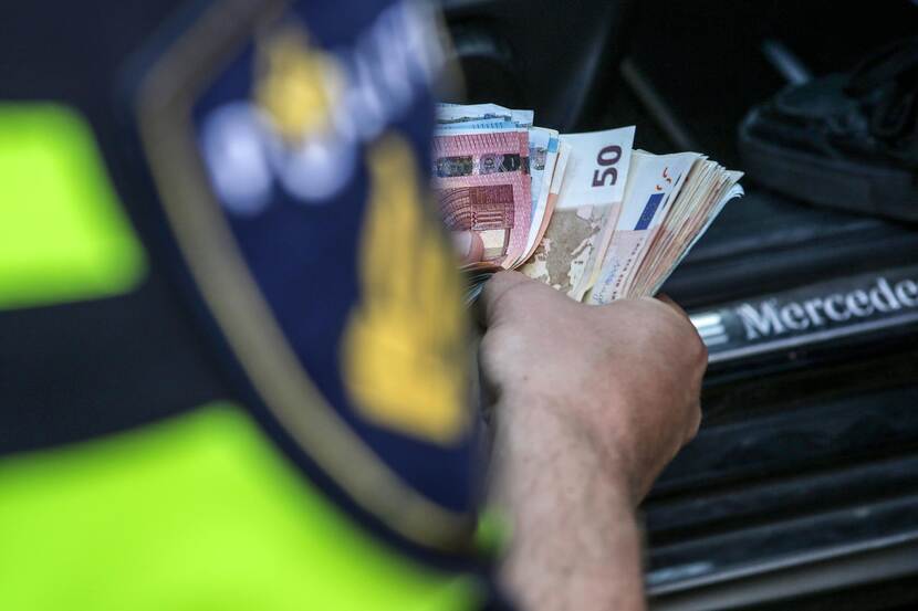 Een politieagent telt geld dat in beslag is genomen van criminelen.