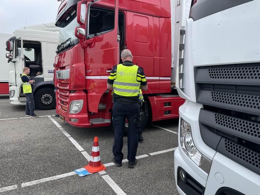 Politieagent staat naast rode vrachtwagen.