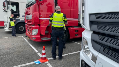 Politieagent staat naast rode vrachtwagen.